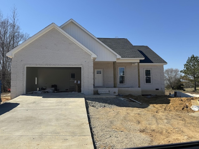 view of front of home with a shingled roof, brick siding, driveway, and a garage