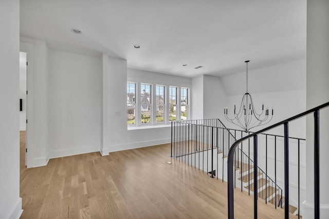 corridor featuring an inviting chandelier, lofted ceiling, and light hardwood / wood-style flooring