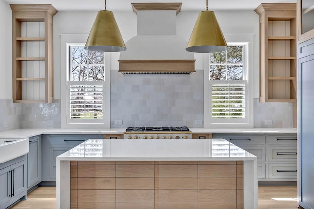 kitchen with pendant lighting, gray cabinetry, backsplash, custom range hood, and a kitchen island