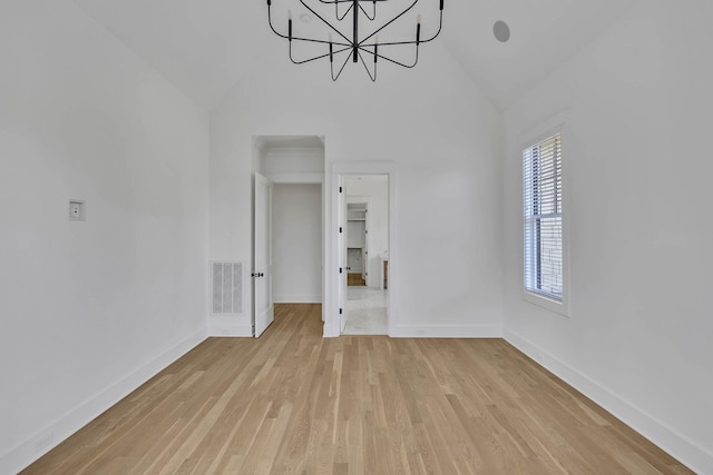 interior space featuring a notable chandelier, vaulted ceiling, light hardwood / wood-style flooring, and a wealth of natural light