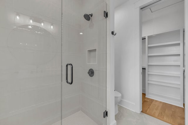 bathroom with hardwood / wood-style flooring, toilet, and a shower with shower door