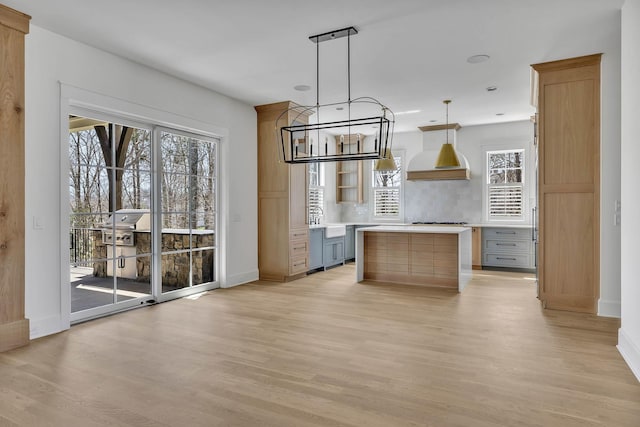 kitchen featuring gray cabinetry, decorative light fixtures, a center island, and light wood-type flooring