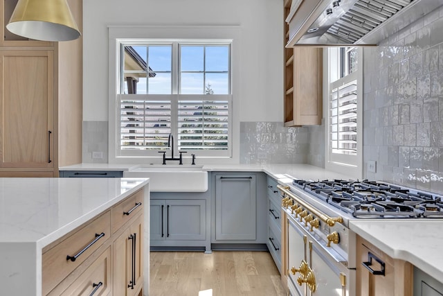 kitchen featuring tasteful backsplash, sink, gray cabinetry, light stone countertops, and custom range hood