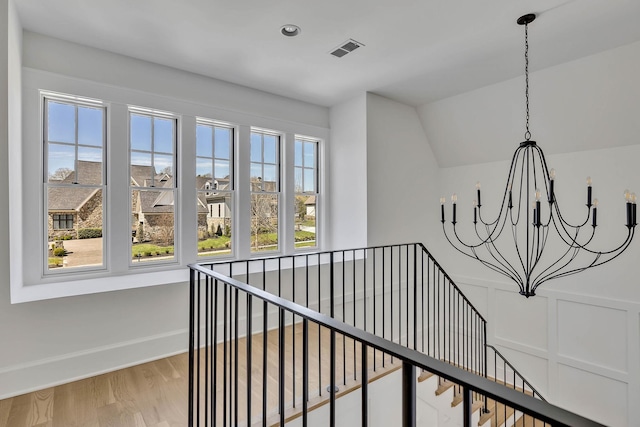 hall featuring hardwood / wood-style flooring, vaulted ceiling, and an inviting chandelier