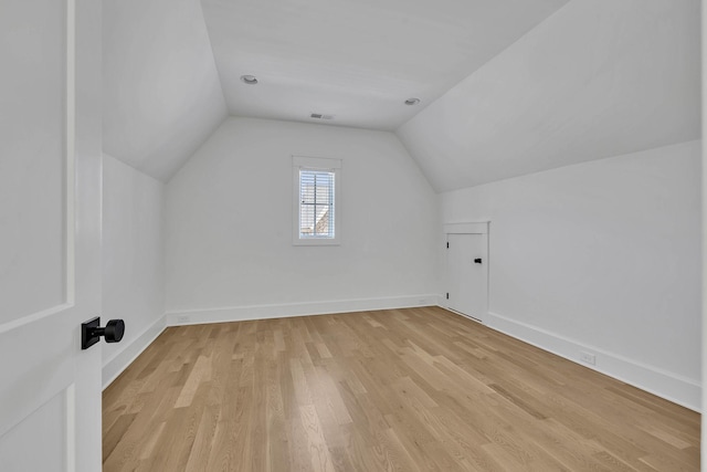 additional living space with vaulted ceiling and light wood-type flooring