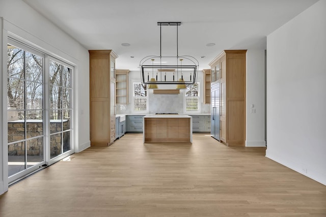 kitchen with light hardwood / wood-style flooring, gray cabinets, paneled built in fridge, a kitchen island, and decorative light fixtures