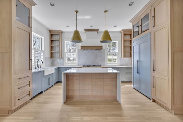 kitchen with pendant lighting, sink, premium range hood, stainless steel appliances, and a kitchen island