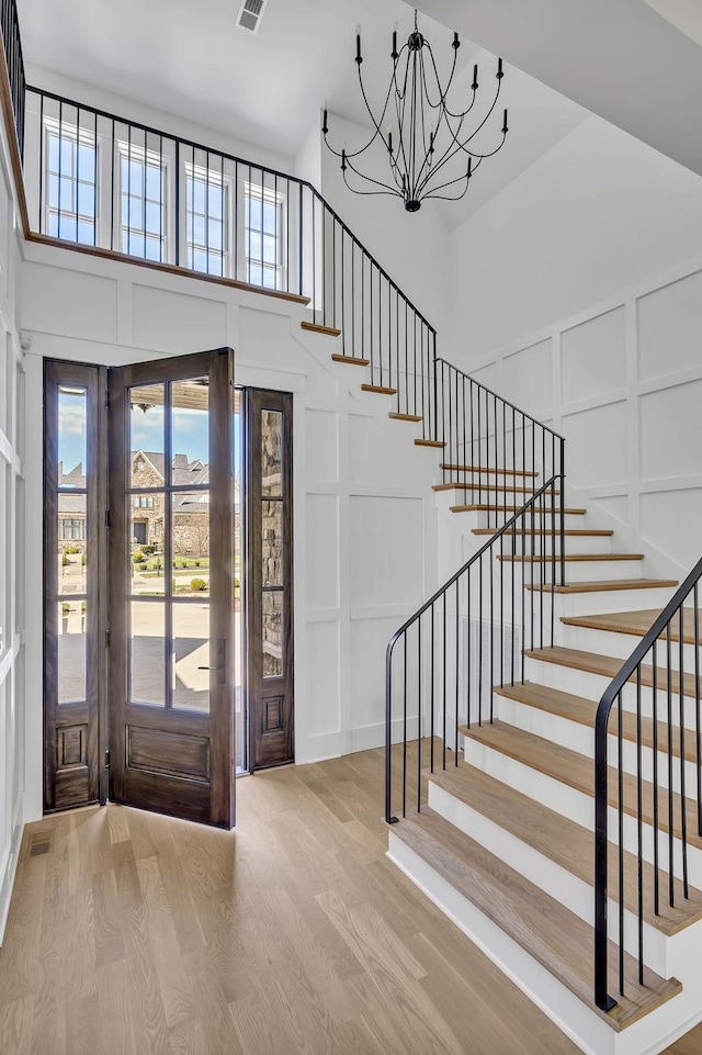 entryway with hardwood / wood-style flooring, a towering ceiling, and a notable chandelier