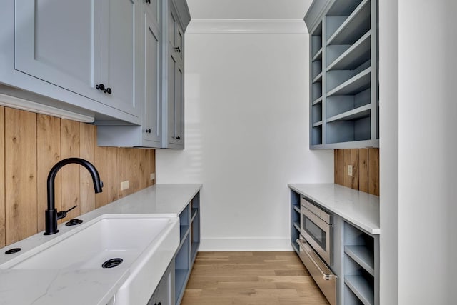 interior space with ornamental molding, light hardwood / wood-style floors, and sink