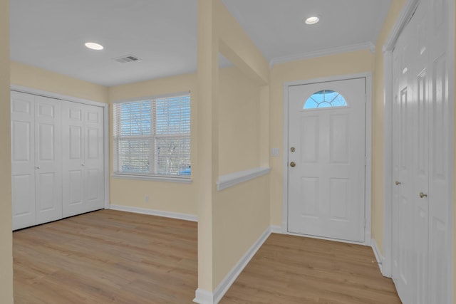 foyer entrance with ornamental molding, light hardwood / wood-style flooring, and a wealth of natural light