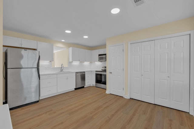 kitchen with stainless steel appliances, light hardwood / wood-style floors, sink, and white cabinets