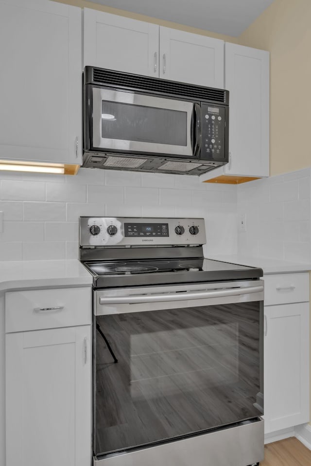 kitchen featuring electric stove, white cabinetry, decorative backsplash, and light wood-type flooring