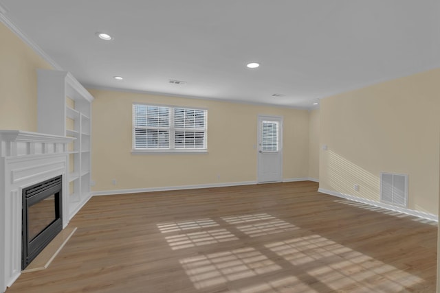 unfurnished living room with crown molding and light hardwood / wood-style flooring