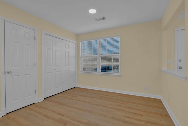 unfurnished bedroom featuring two closets and light hardwood / wood-style flooring