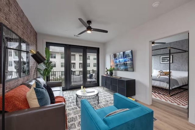 living room featuring hardwood / wood-style flooring, ceiling fan, and brick wall