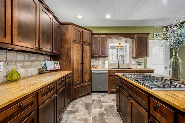 kitchen featuring sink, appliances with stainless steel finishes, tasteful backsplash, dark brown cabinetry, and wood counters