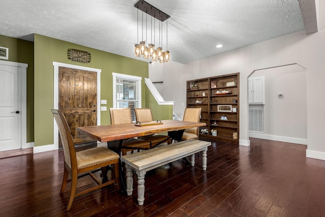 dining space featuring dark wood-type flooring, a notable chandelier, and a textured ceiling