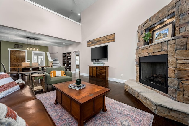 living room featuring dark hardwood / wood-style floors, a fireplace, and a towering ceiling