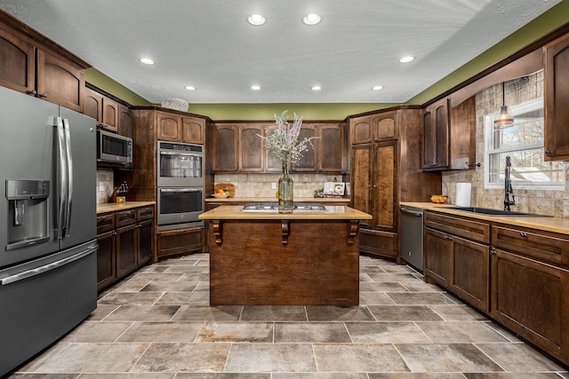 kitchen featuring dark brown cabinetry, sink, decorative backsplash, and stainless steel appliances