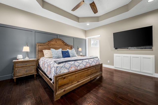 bedroom featuring a tray ceiling, dark wood-type flooring, and ceiling fan