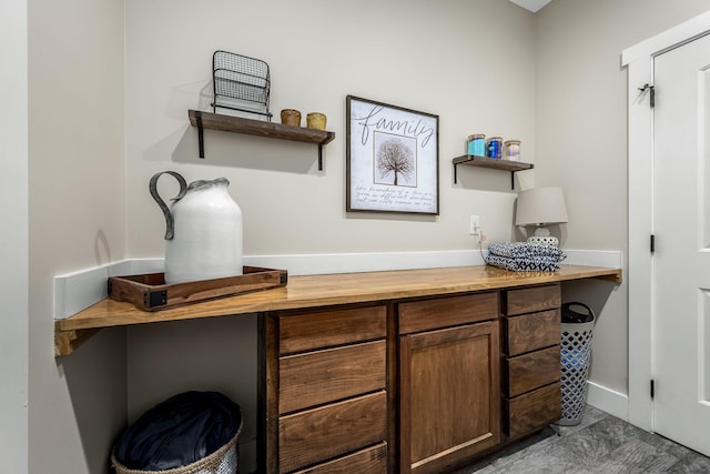 bar featuring wood counters, dark brown cabinetry, and built in desk