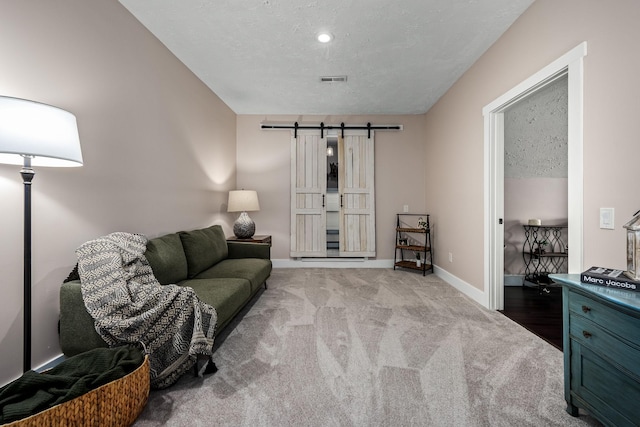 living room featuring a barn door, light carpet, and a textured ceiling