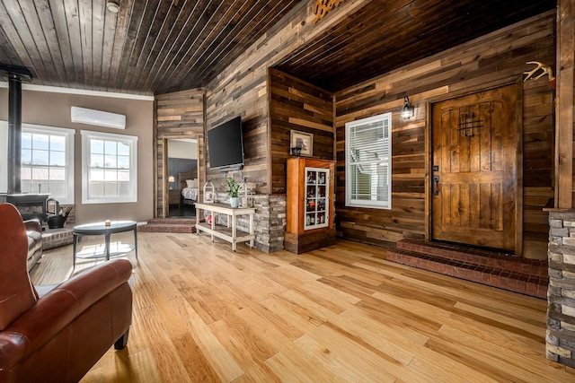 living room with a wall mounted air conditioner, wood ceiling, wooden walls, and light wood-type flooring