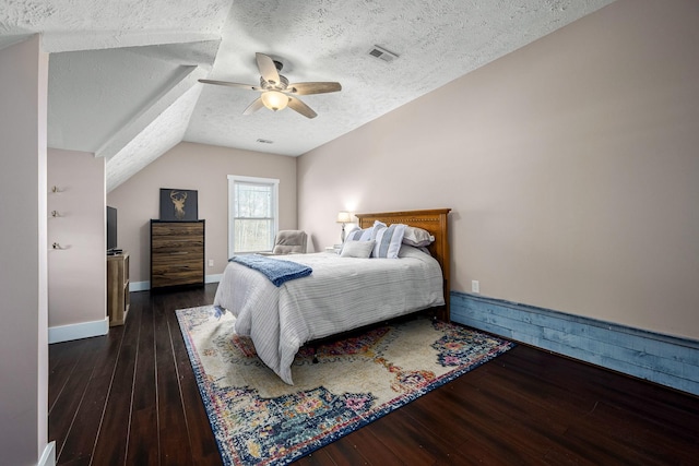 bedroom featuring ceiling fan, dark hardwood / wood-style flooring, vaulted ceiling, and a textured ceiling