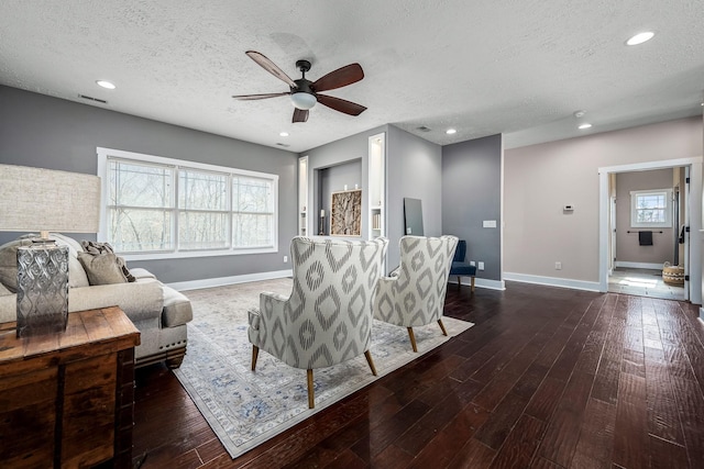 living room with dark wood-type flooring, ceiling fan, plenty of natural light, and a textured ceiling