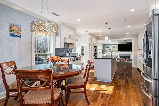 dining space with crown molding, dark hardwood / wood-style floors, and sink