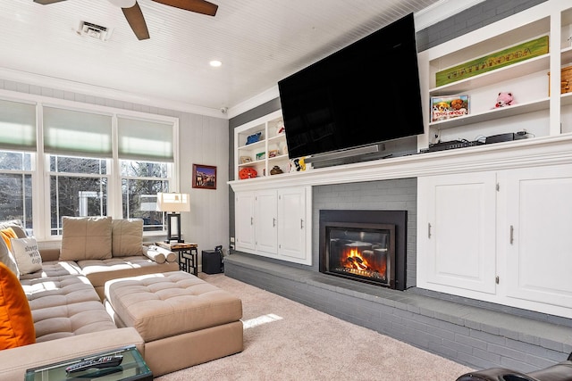 carpeted living room with crown molding, ceiling fan, and a brick fireplace