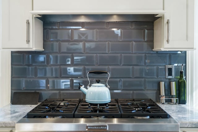 interior details with light stone countertops, white cabinets, and backsplash