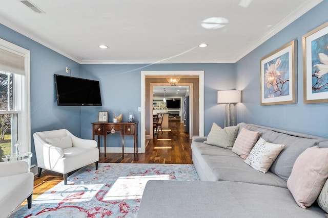 living room with dark hardwood / wood-style flooring, crown molding, a wealth of natural light, and a chandelier