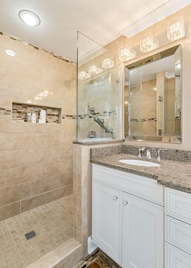 bathroom featuring vanity, ornamental molding, and tiled shower