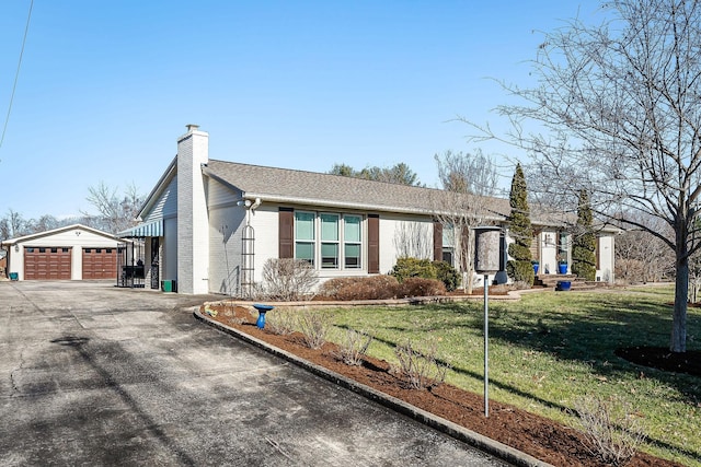 ranch-style home featuring an outbuilding, a garage, and a front yard