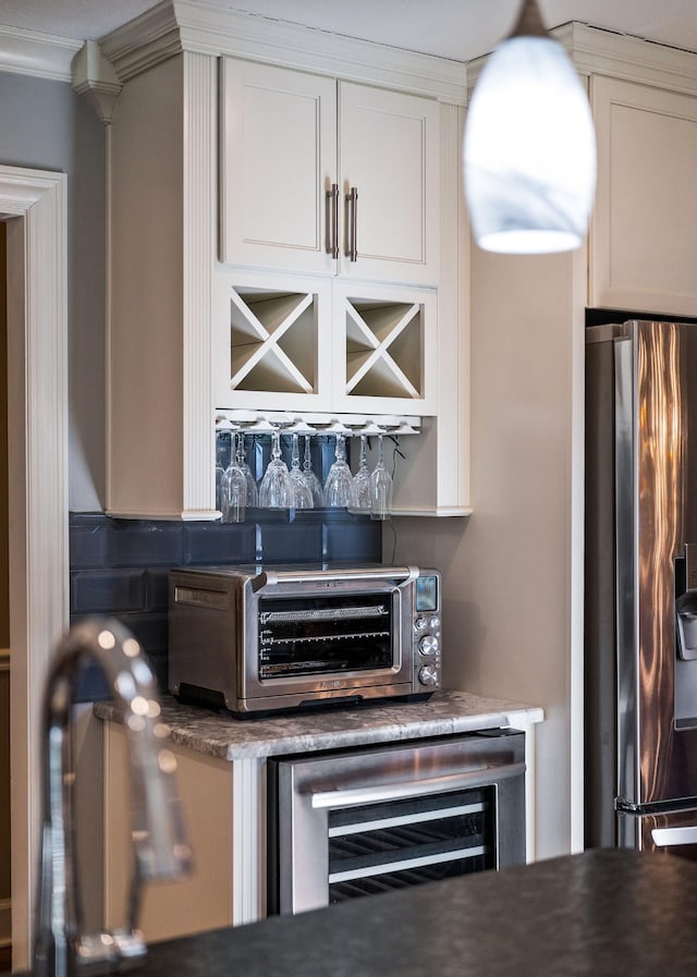 bar with stainless steel fridge, ornamental molding, beverage cooler, and white cabinets