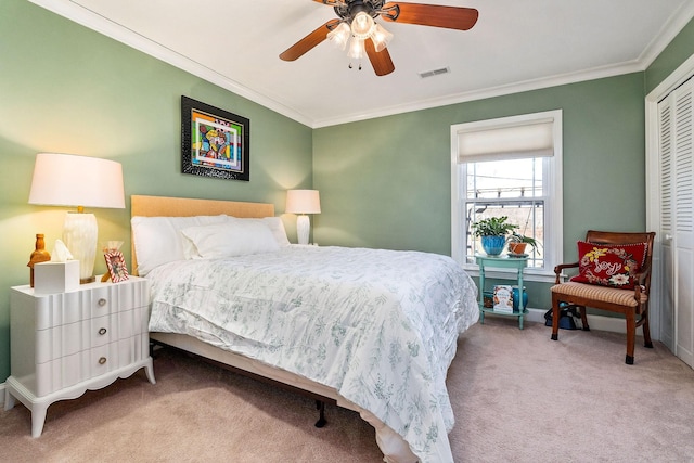 bedroom featuring crown molding, light colored carpet, ceiling fan, and a closet