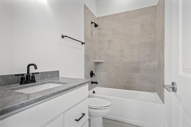 full bathroom featuring tiled shower / bath, vanity, and toilet