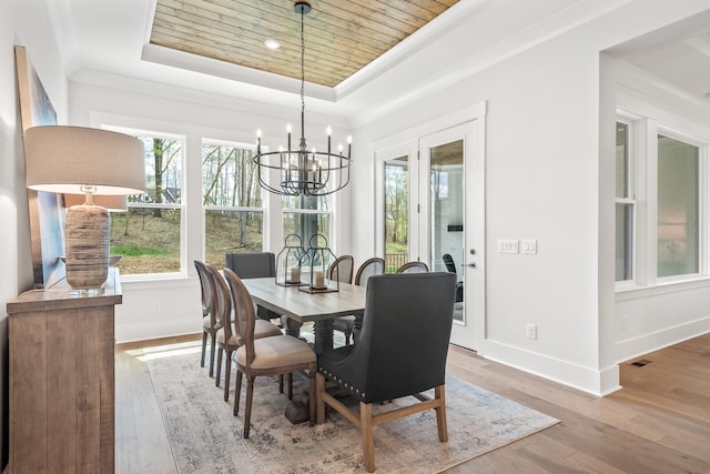 dining space with a chandelier, ornamental molding, wood ceiling, light hardwood / wood-style floors, and a raised ceiling