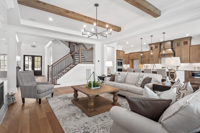 living room featuring sink, light hardwood / wood-style flooring, a notable chandelier, beam ceiling, and french doors