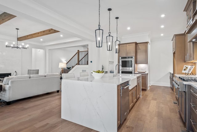 kitchen featuring pendant lighting, hardwood / wood-style flooring, beam ceiling, a large island with sink, and stainless steel double oven