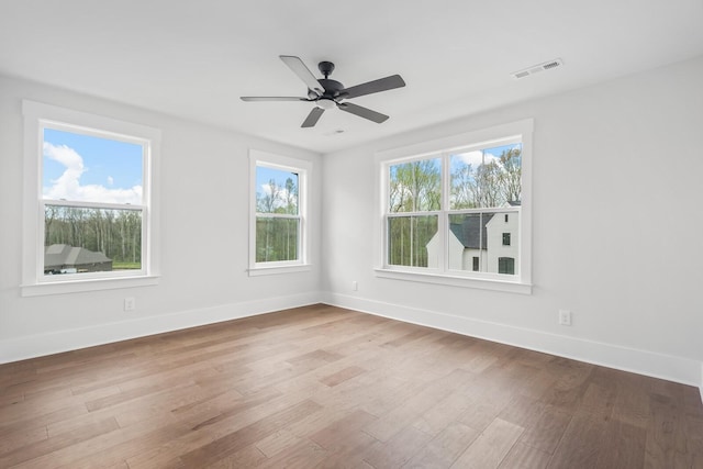 empty room with hardwood / wood-style flooring, a healthy amount of sunlight, and ceiling fan