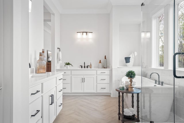 bathroom featuring ornamental molding, parquet flooring, a healthy amount of sunlight, and a tub to relax in