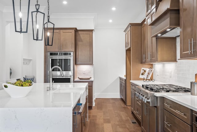 kitchen featuring pendant lighting, tasteful backsplash, hardwood / wood-style flooring, stainless steel appliances, and custom range hood