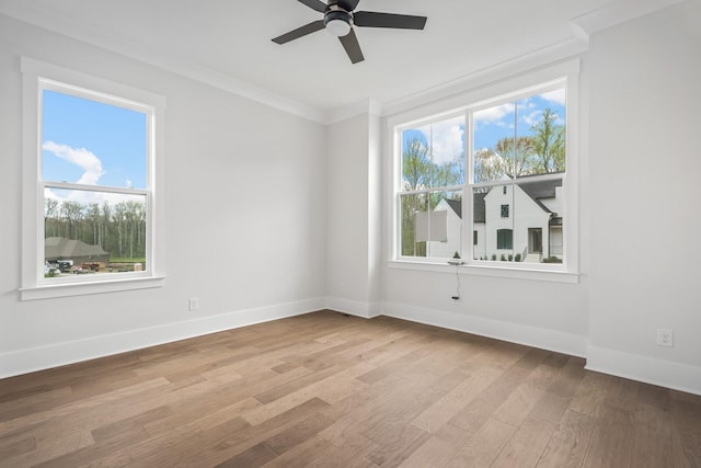 spare room featuring crown molding, a healthy amount of sunlight, and light hardwood / wood-style floors