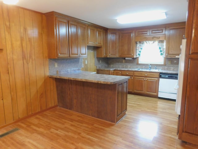 kitchen with light wood-type flooring, sink, white dishwasher, and kitchen peninsula