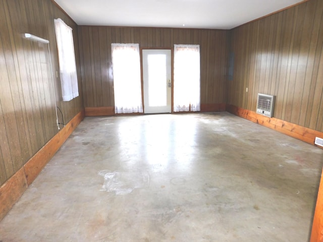 unfurnished room with heating unit, concrete floors, and wood walls