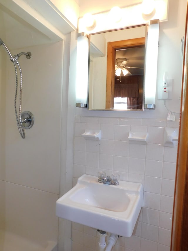 bathroom with walk in shower, ceiling fan, sink, and tile walls