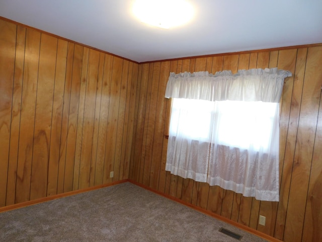 carpeted empty room with wood walls