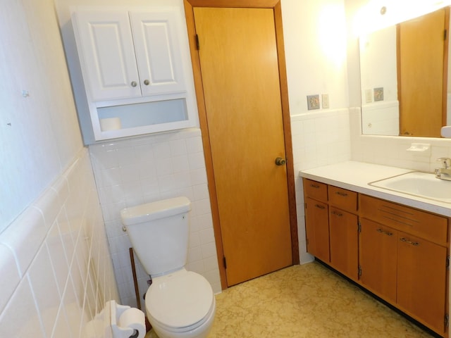 bathroom with tile walls, vanity, and toilet